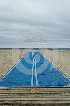 A blue runner stretched across a sandy beach leads to the horizon 2