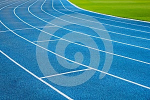 Blue running treadmill track with lane numbers in stadium outdoors.Starting grid of race track at the stadium