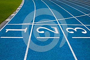 Blue running treadmill track with lane numbers in stadium outdoors.Starting grid of race track at the stadium