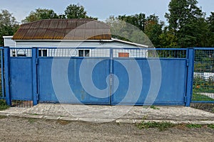 Blue rural metal gate and part of the fence in the street