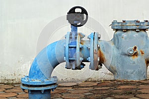 Blue rusty metal industrial water pipes with a valve.