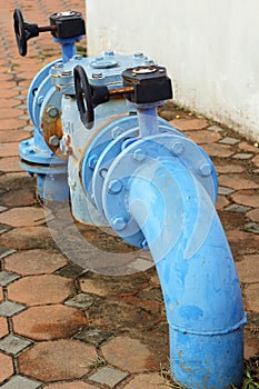 Blue rusty metal industrial water pipes with a valve.