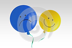 Blue sad balloon and yellow happy balloon flying away on white background - Prevalence of negative over positive mood concept photo