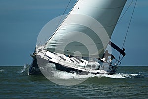 Blue sailboat taking speed under blue sky