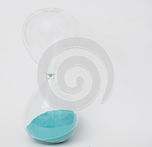 Blue sand in a sand clock on white background