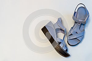 Blue sandals on light background. Stylish summer women`s leather shoes, top view, copy space