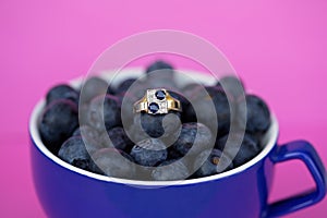Blue Sapphire And Diamond Gold Ring In A Cup Of Blueberries
