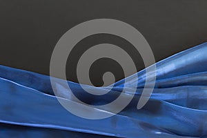 Blue satin fabric folds on black background with copy blank space