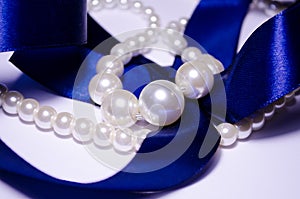 Blue satin ribbon with pearl jewelry. Luxurious decoration. For jewelry sites, blogs about fashion, style, jewelry. Snow-white