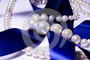 Blue satin ribbon with pearl jewelry. Luxurious decoration. For jewelry sites, blogs about fashion, style, jewelry. Snow-white