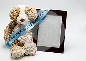 Plush teddy bear and empty picture frame with `It`s A Boy` ribbon