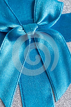 Blue satin ribbon on a silver background. Closeup.