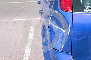 Blue scratched car with damaged paint in crash accident or parking lot and dented damage of metal body from collision photo