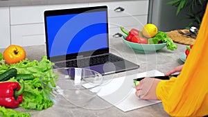 Blue screen laptop: Woman in kitchen greets tells chef listen slices cucumber