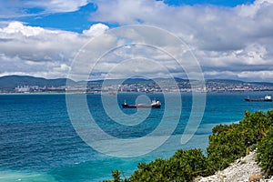 Blue sea with cargo ships against blue cloudy sky