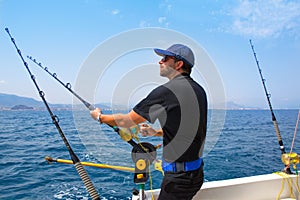 Blue sea fisherman in trolling boat with downrigger