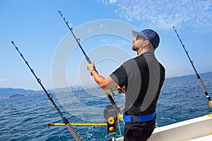 Blue sea fisherman in trolling boat with downrigger