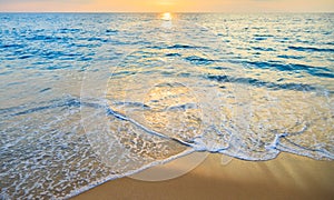 Blue sea and golden sand with sunset background