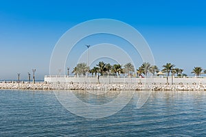 Blue sea and green date palm trees in the corniche park in Dammam, Saudi Arabia