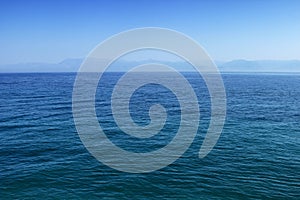 Blue sea or ocean water surface with horizon and sky