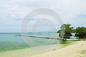 Blue sea sand beach with wooden pier landscape. Romantic seaside view toned photo.