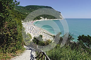Blue sea in sunny day close to the forest in the Conero natural park - Italy. During touristic season is full of umbrella and