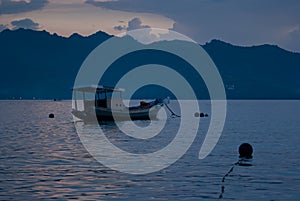 Blue sea sunset, evening - pastel pink sky, clouds, blue foggy mountains on horizon, calm smooth water with breeze, floated.