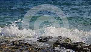 Blue sea view with white wave splashing over beach rock. Volcanic seaside during high tide