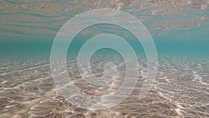 Blue sea water sunny refractions on sandy bottom, underwater loop-ready background