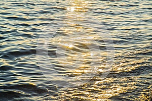 Blue sea water surface at sunset with sparks