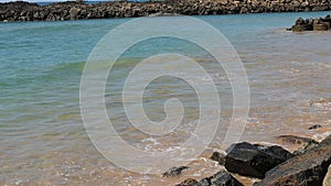 Blue sea waves impact rocky coast on the beach