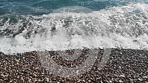 Blue sea waves with white foam washed multicolored stones on a pebble shore - 19s