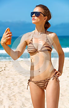 Young woman on beach applying suntan lotion