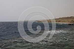 Blue sea and yellow sand beach with pier