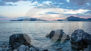 Blue seascape with stoney beach at sunset. Stone coastline with islands on the skyline for publication, poster, calendar