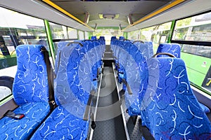 Blue seats for passengers in saloon of empty city bus