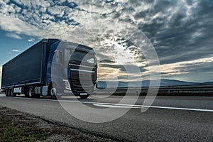 Blue semi trailer truck on a highway at sunset