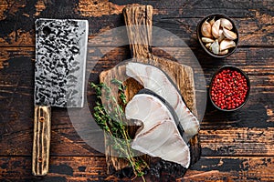 Blue Shark raw fish steaks on a cutting board with cleaver. Dark wooden background. Top view