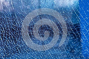 Blue shattered glass completely covered with cracks, creating a fragmented, textured surface with sharp patterns and a dramatic
