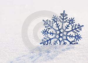 Blue shiny snowflake on brilliant snow surface. Winter natural blur abstract white blurred bokeh background.