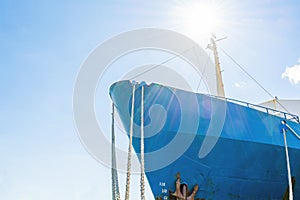 Blue ship`s nose on a blue sky background. Ship`s ropes. Bright sun above the deck.