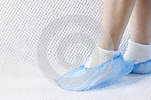 Blue shoe covers put on legs on a white background. Copy space - concept of cleanliness, health, disease prevention