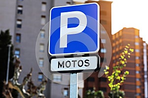 Blue sign with a big white P letter and inscription motos indicating the parking for motorcycles and scooters, on