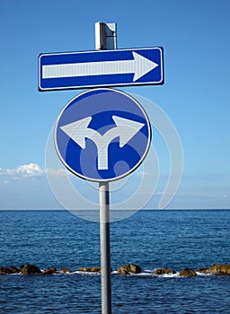 Blue signs for directions on background with sea and sky