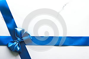Blue silk ribbon and bow on luxury marble background, holiday flatlay backdrop