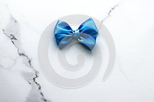 Blue silk ribbon and bow on luxury marble background, holiday flatlay backdrop