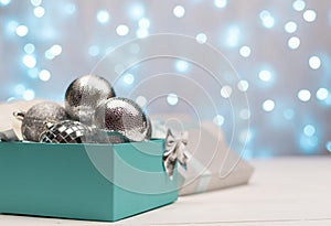 Blue and silver box with silver Christmas balls on the background of blue bokeh lights 2020