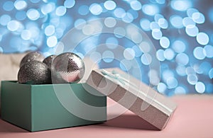 Blue and silver box with silver Christmas balls on the background of blue bokeh lights New Yar card