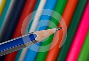 Blue and silver striped wood pencil crayon held in front of a row of pencils