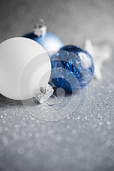 Blue, silver and white xmas ornaments on glitter holiday background. Merry christmas card.